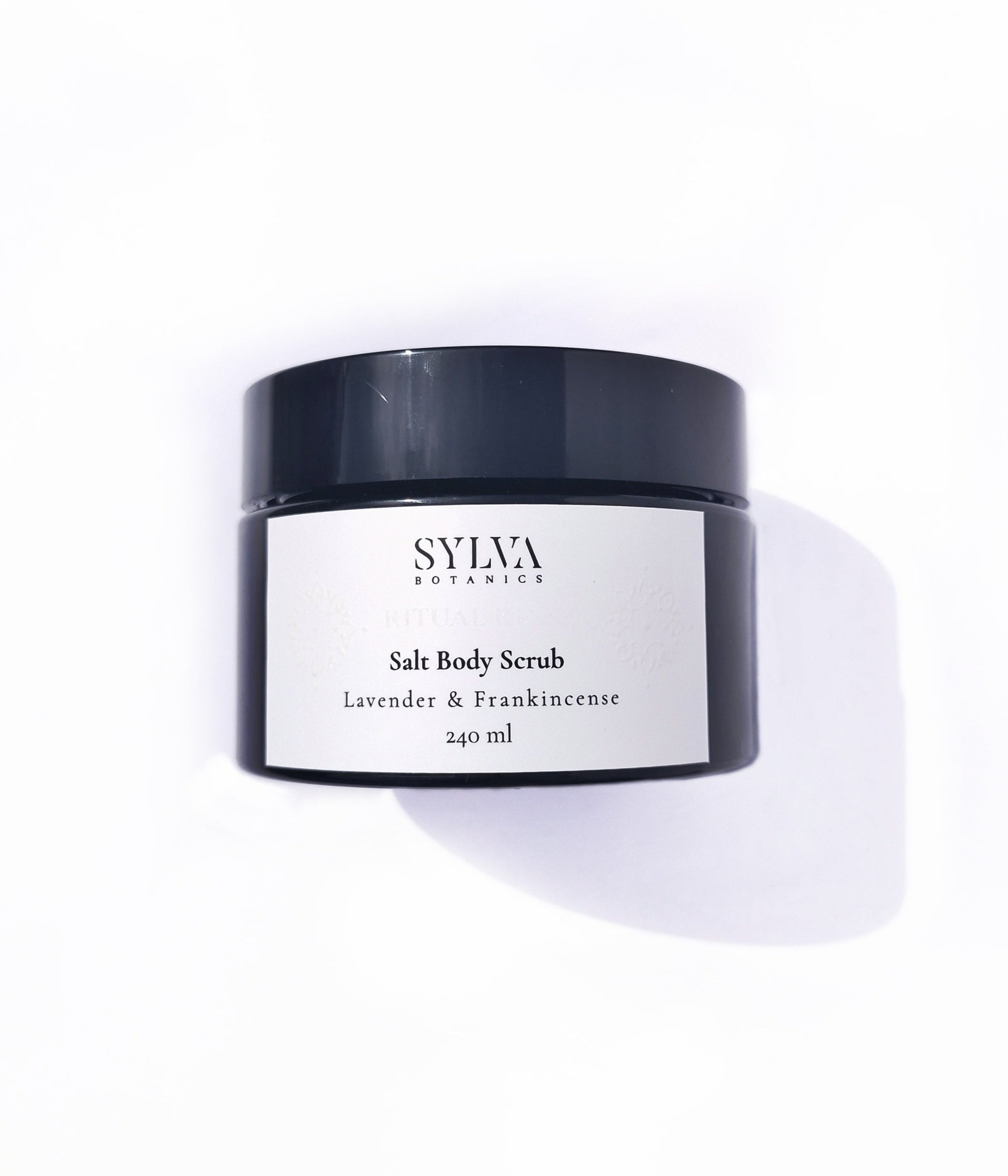 Black jar with white label containing Sylva Botanics lavender and frankincense salt body scrub on white background.