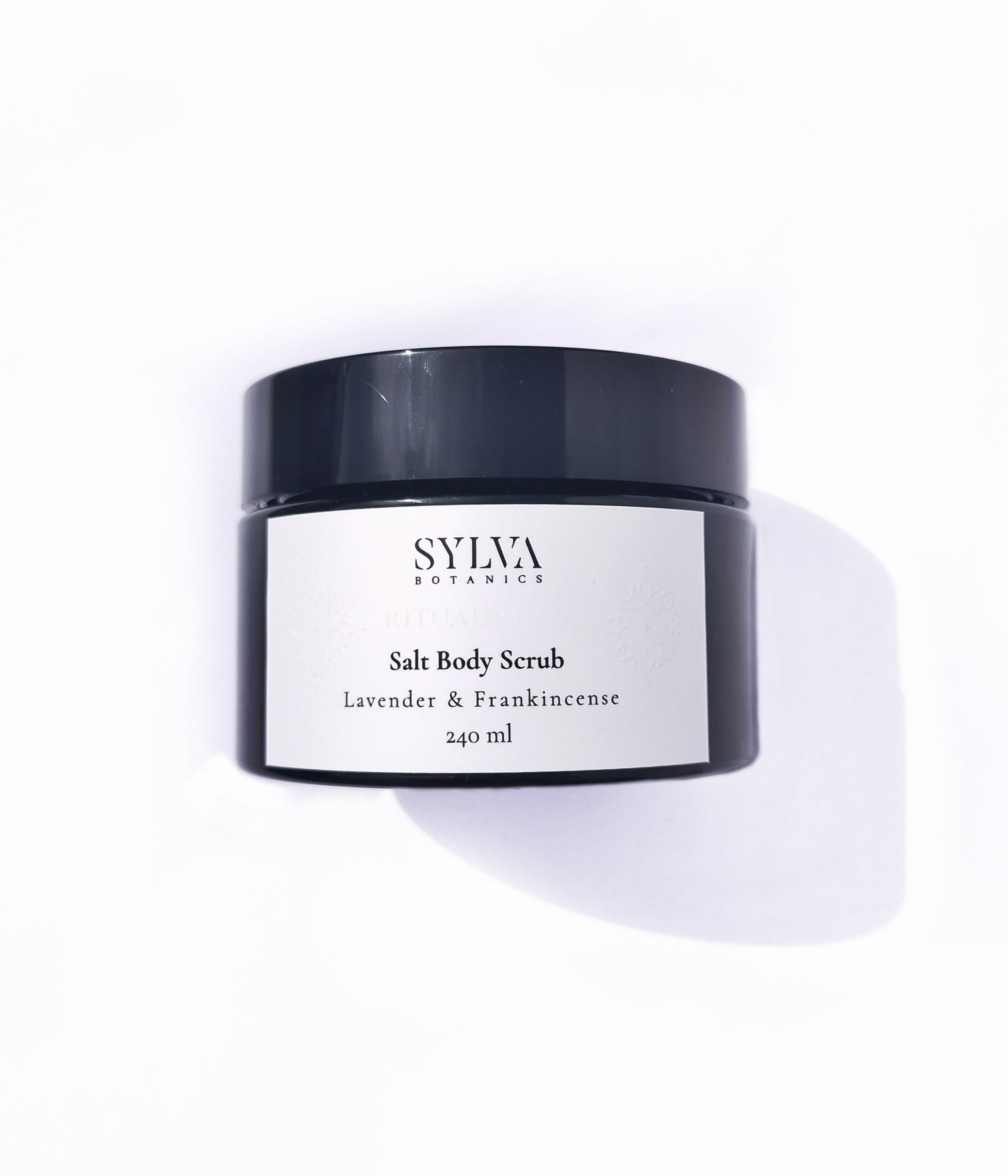 Black jar with white label containing Sylva Botanics lavender and frankincense salt body scrub on white background.